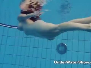 Redheaded seductress nadando desnuda en la piscina